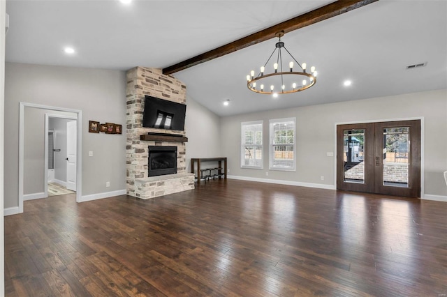 unfurnished living room with a chandelier, beamed ceiling, dark wood-type flooring, a fireplace, and french doors