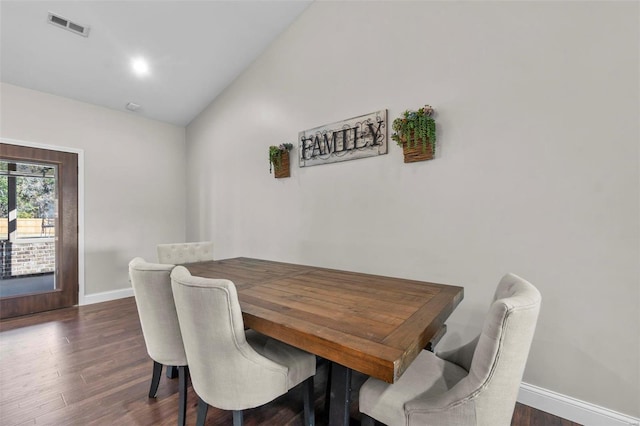 dining area featuring dark wood-type flooring and high vaulted ceiling