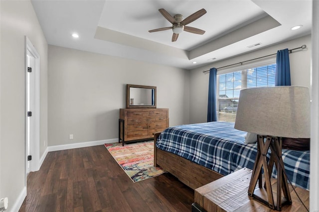 bedroom with a raised ceiling, dark hardwood / wood-style floors, and ceiling fan