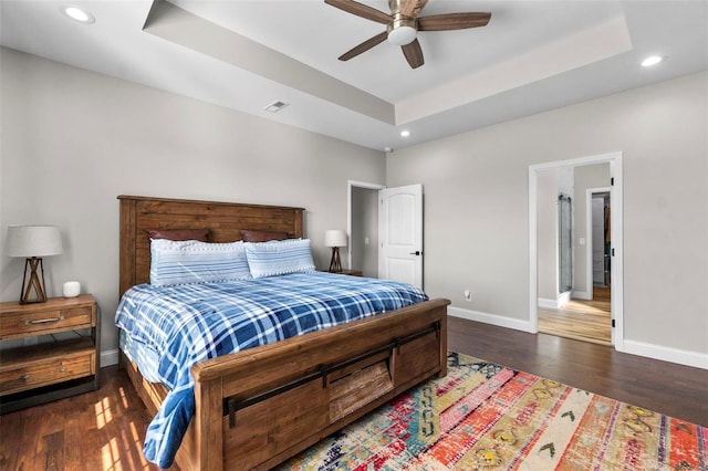 bedroom featuring a tray ceiling, dark wood-type flooring, and ceiling fan