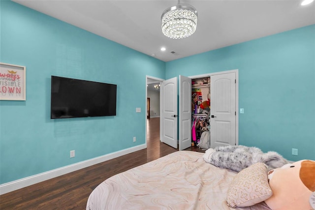 bedroom featuring an inviting chandelier, dark wood-type flooring, and a closet