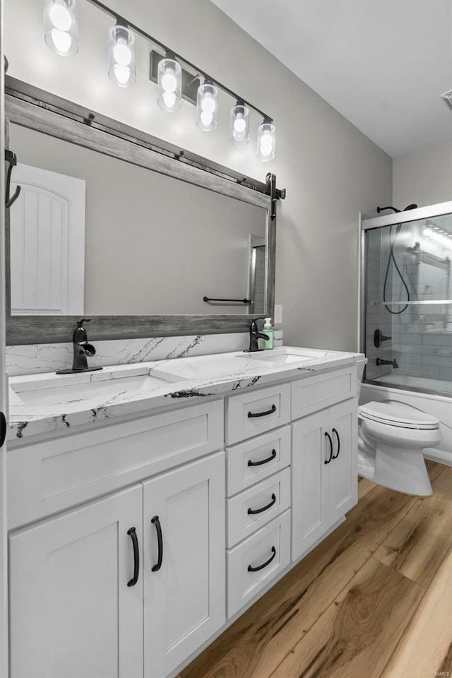 full bathroom with vanity, toilet, shower / bath combination with glass door, and hardwood / wood-style floors