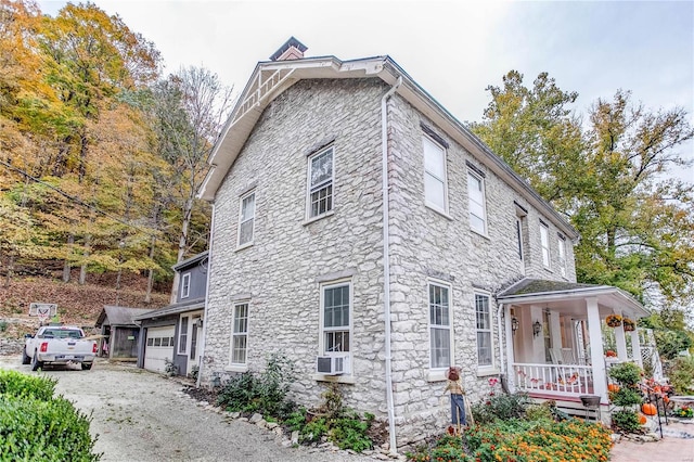 view of property exterior featuring a porch, cooling unit, and a garage