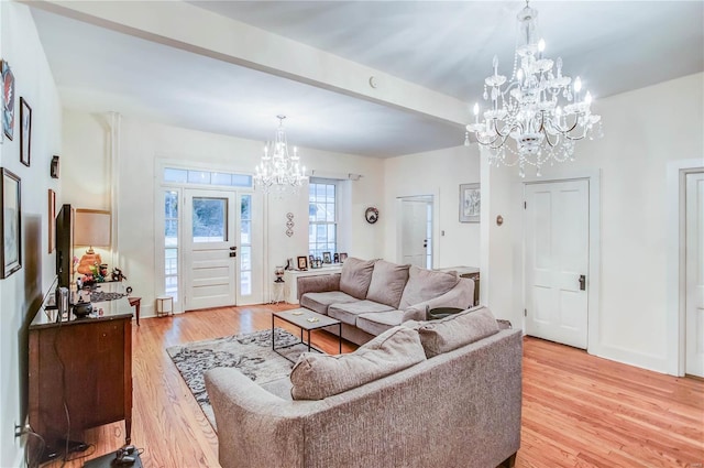 living room with an inviting chandelier, beam ceiling, and light wood-type flooring