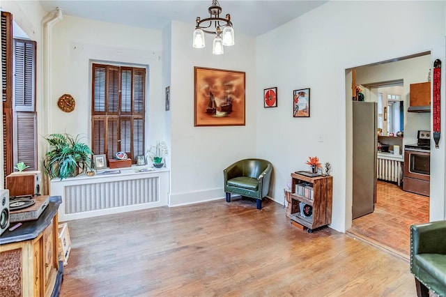 sitting room with light hardwood / wood-style floors, a notable chandelier, and radiator