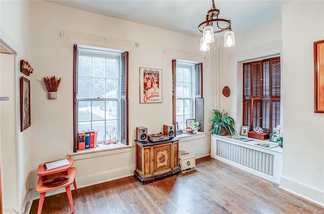 interior space with radiator, light hardwood / wood-style floors, and an inviting chandelier