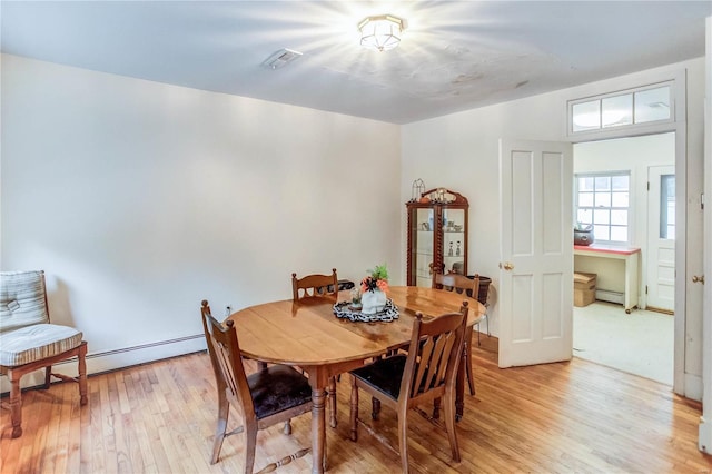 dining area featuring a baseboard heating unit and light wood-type flooring