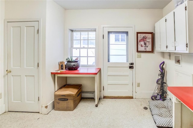 interior space featuring hookup for a washing machine, light carpet, cabinets, and a baseboard heating unit