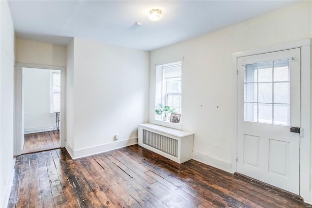 entryway with dark wood-type flooring and radiator heating unit