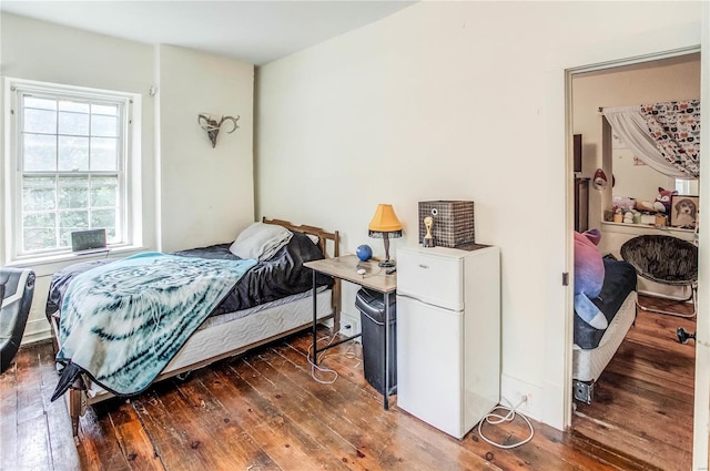 bedroom with white refrigerator and dark hardwood / wood-style floors