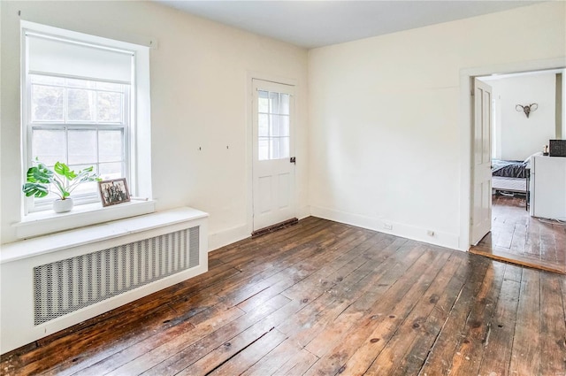 foyer entrance featuring radiator heating unit and dark hardwood / wood-style flooring