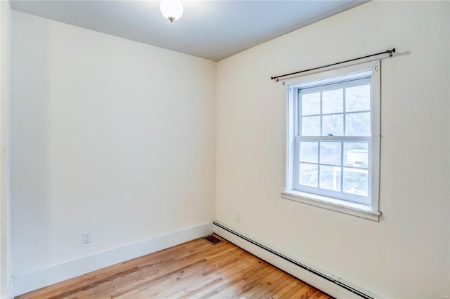 empty room featuring a baseboard heating unit and light wood-type flooring