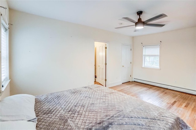 bedroom with ceiling fan, light hardwood / wood-style flooring, and baseboard heating