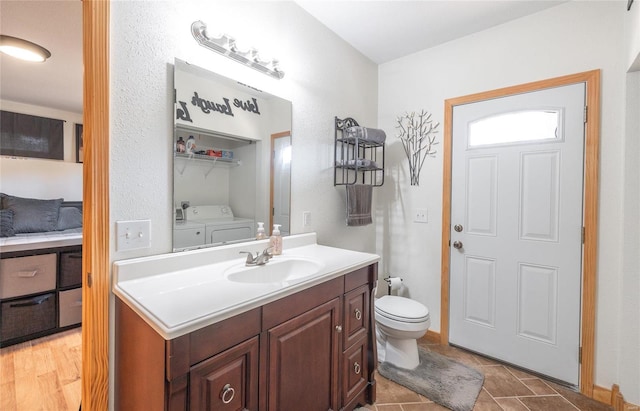 bathroom featuring washing machine and dryer, tile patterned floors, toilet, and vanity