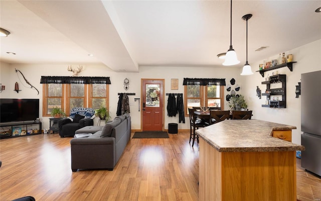 kitchen with stainless steel fridge, light wood-type flooring, and decorative light fixtures