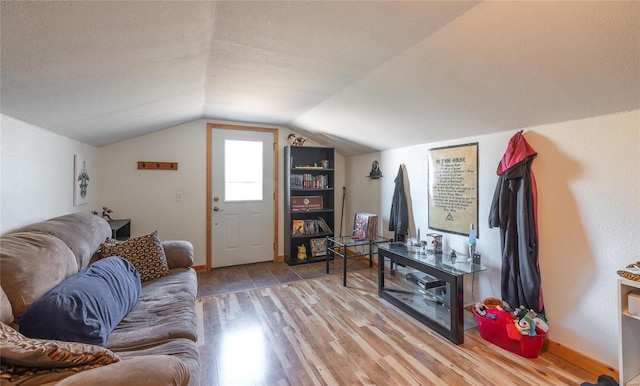 living room featuring light hardwood / wood-style floors, a textured ceiling, and vaulted ceiling