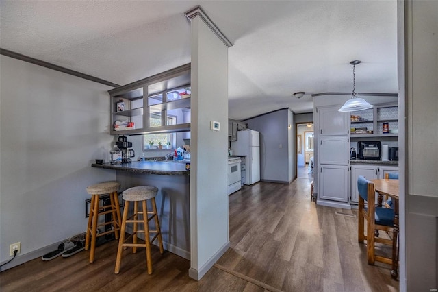 kitchen with white appliances, a textured ceiling, crown molding, a breakfast bar area, and dark hardwood / wood-style floors