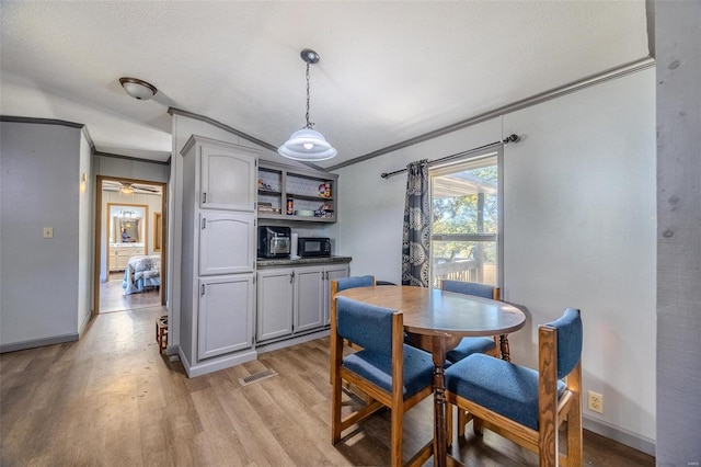 dining space with ornamental molding, a textured ceiling, light hardwood / wood-style floors, and ceiling fan