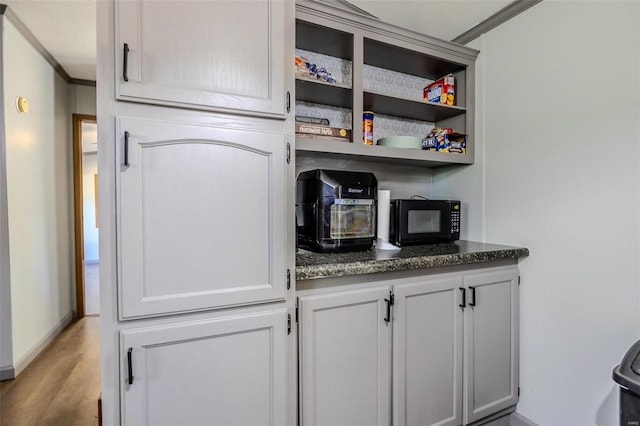 bar featuring ornamental molding, light hardwood / wood-style flooring, and white cabinetry