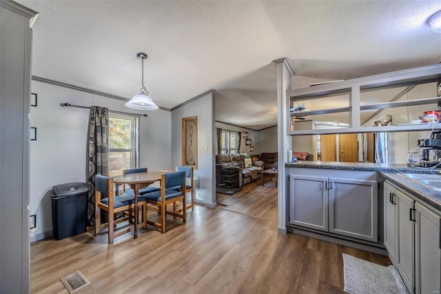 kitchen featuring gray cabinets, pendant lighting, wood-type flooring, and a textured ceiling