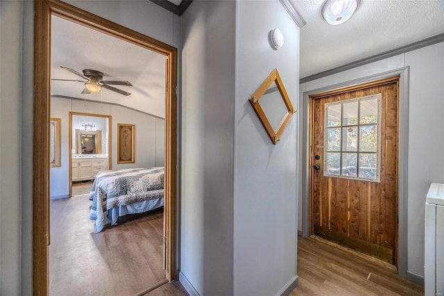 hallway with crown molding, a textured ceiling, light wood-type flooring, and wooden walls