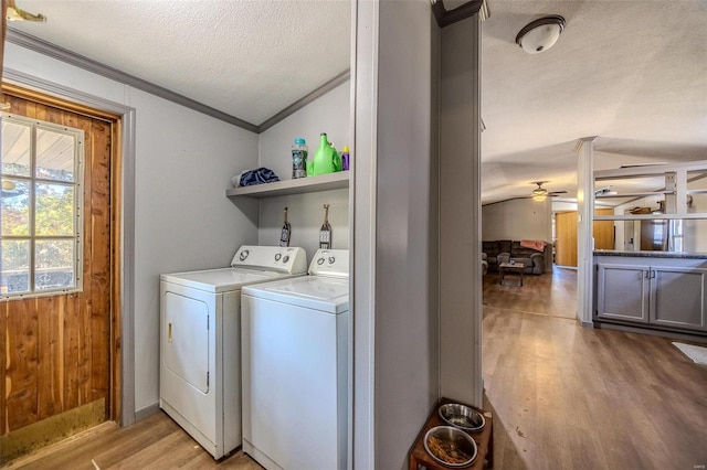 clothes washing area with light hardwood / wood-style flooring, ornamental molding, washing machine and dryer, a textured ceiling, and ceiling fan