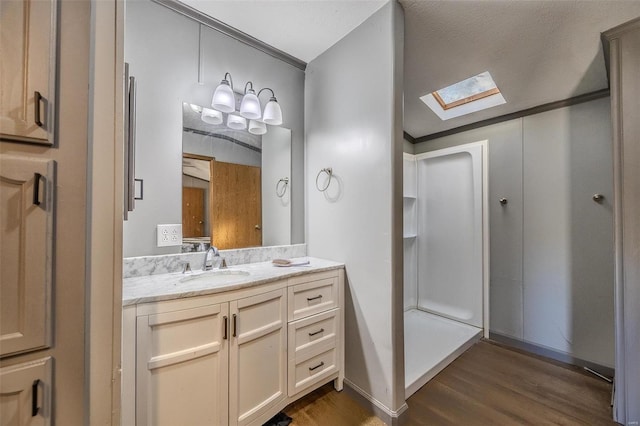 bathroom with a textured ceiling, hardwood / wood-style flooring, ornamental molding, a skylight, and vanity