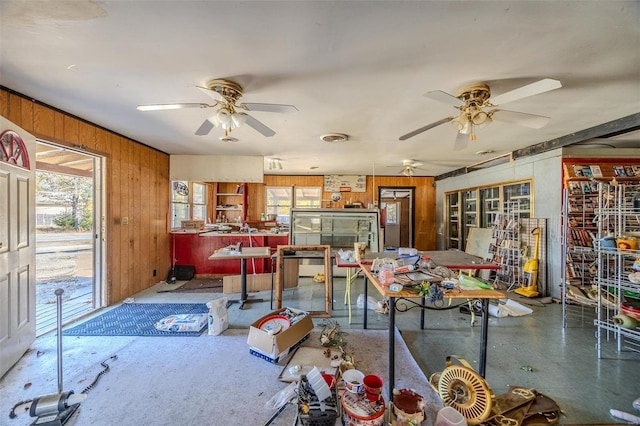 dining space with wooden walls and ceiling fan