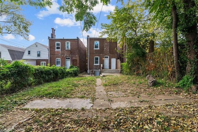 rear view of property with brick siding, a chimney, and entry steps