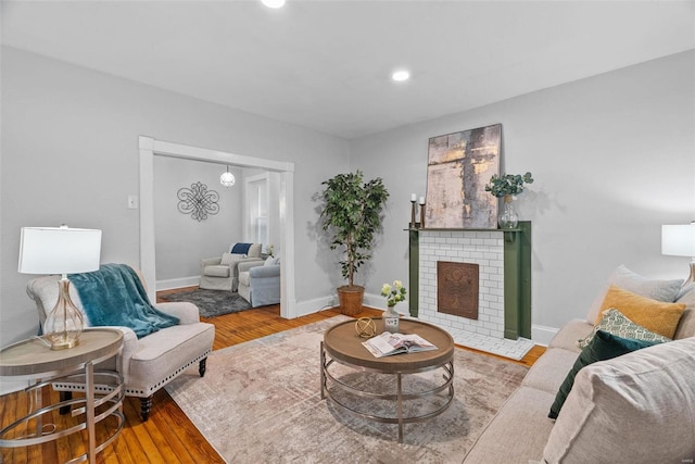 living room with a brick fireplace and wood-type flooring