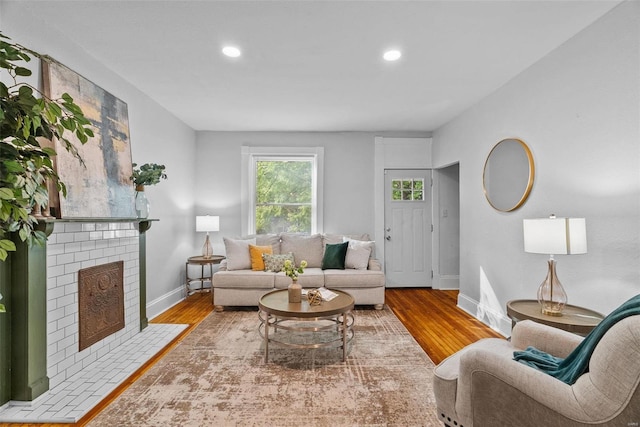 living area featuring recessed lighting, a brick fireplace, baseboards, and wood finished floors