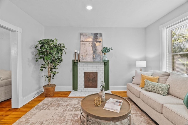 living area with a brick fireplace, recessed lighting, wood finished floors, and baseboards