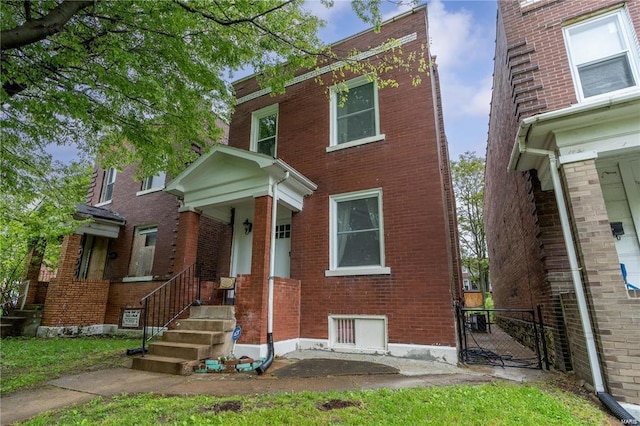 view of front facade featuring brick siding and a gate