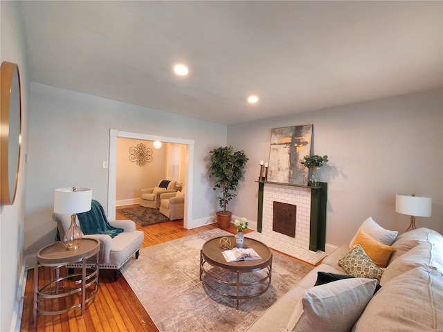 living area featuring a brick fireplace, recessed lighting, baseboards, and wood-type flooring