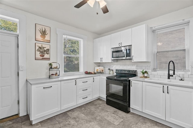 kitchen with stainless steel microwave, backsplash, black range with electric cooktop, light countertops, and a sink