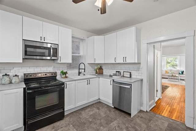 kitchen featuring backsplash, light countertops, appliances with stainless steel finishes, white cabinets, and a sink