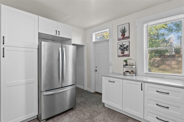 kitchen with white cabinetry, light countertops, a healthy amount of sunlight, and freestanding refrigerator