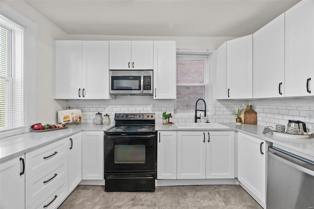 kitchen featuring white cabinets, appliances with stainless steel finishes, light countertops, and a sink