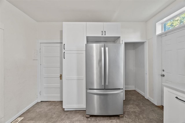 kitchen with baseboards, white cabinets, light countertops, and freestanding refrigerator