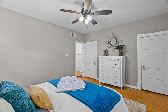 bedroom featuring a ceiling fan, light wood-style floors, visible vents, and baseboards