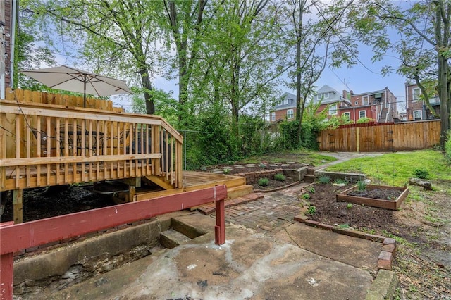 view of patio featuring a deck, a vegetable garden, and fence