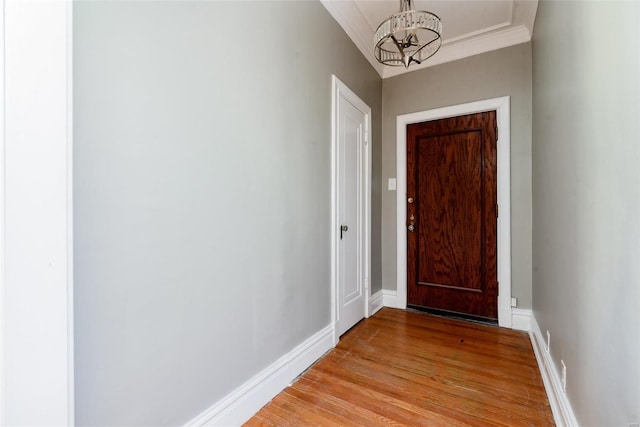 doorway to outside with ornamental molding, light hardwood / wood-style floors, and an inviting chandelier