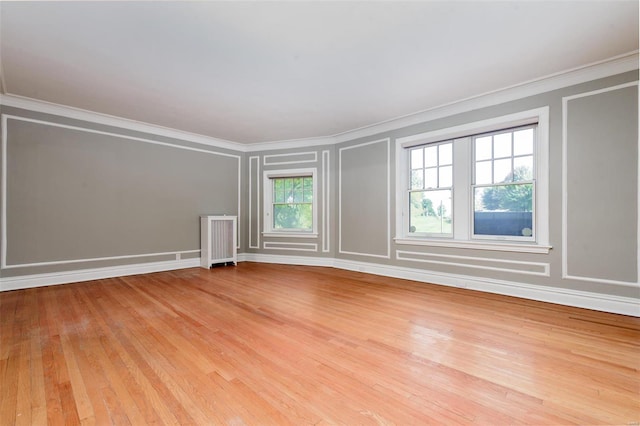 spare room with crown molding, radiator heating unit, and light hardwood / wood-style floors