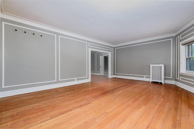 unfurnished room featuring light hardwood / wood-style flooring, ornamental molding, and radiator