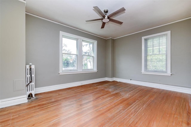 spare room featuring light hardwood / wood-style floors, radiator heating unit, and a wealth of natural light