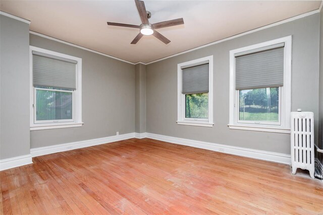 empty room with crown molding, light hardwood / wood-style flooring, ceiling fan, and radiator