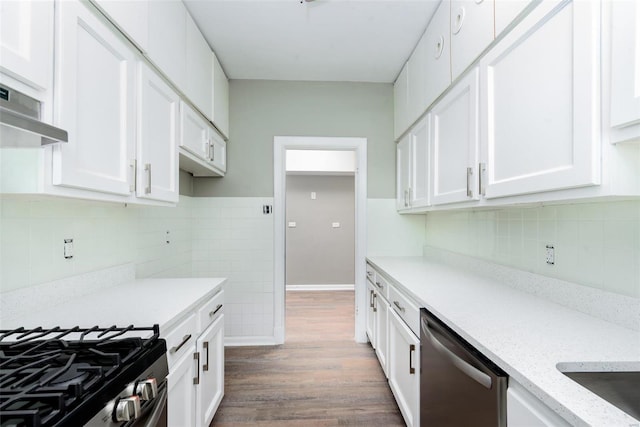 kitchen with hardwood / wood-style floors, dishwasher, white cabinets, and light stone countertops