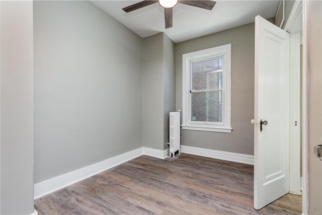 empty room with ceiling fan, wood-type flooring, and radiator