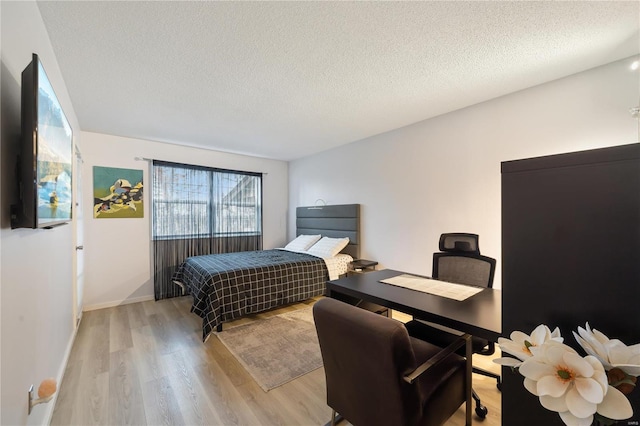 bedroom with light hardwood / wood-style floors and a textured ceiling