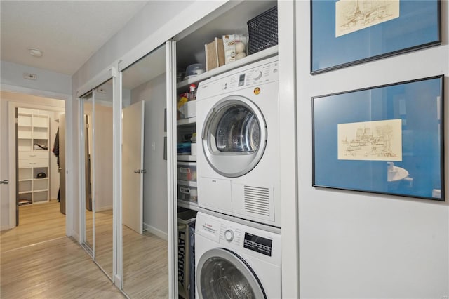 laundry room with hardwood / wood-style flooring and stacked washer / drying machine